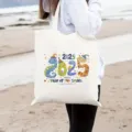 Vista dettagliata del design della borsa in tela con tema serpente 2025 presentata sulla spiaggia. - Stampa Anno del Serpente / 42x35cm