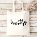 Vista dettagliata di borsa in tela bianca con stampa nera su sfondo in legno rustico. - Stampa Lettere Inglesi Worthy / 42x35cm