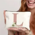 Trousse de maquillage en toile avec lettre L et motif floral, pochette de voyage idéale. - Lettre L