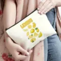 Primo piano borsa cosmetica in tela con stampa di limoni gialli e pratica chiusura a cerniera. - Stampa Frutta Limone