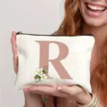 Trousse de maquillage en toile blanche avec lettre R et motif floral, organiseur de voyage élégant. - Lettre R