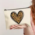 Close-up detail of a beige canvas makeup bag featuring a trendy leopard print heart design. - Style 8