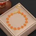 Exquisite gold-tone titanium steel clover bracelet featuring vibrant orange gemstone details. - Gold Orange Zirconia