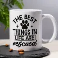 Close-up detail of white ceramic coffee mug featuring black pet rescue quote print design. - Style 9