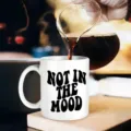 Detailansicht der weißen Keramiktasse mit schwarzem Text, schöne Kaffeegießen Szene. - Englisches Slogan-Stil