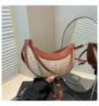 Gros plan détaillé du sac bandoulière élégant en paille demi-lune avec bordure en cuir marron. - Marron