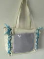 Vista detallada del bolso tote blanco con lazos azules y bolsillo de malla transparente. - Sin Correa Larga / Beige (Cinta Azul)