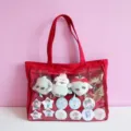 Red canvas ita bag detail showing transparent front pocket with cute anime plush toys and pins. - Red