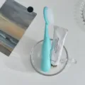 Gros plan sur la brosse à dents souple à tête large dans un verre, style de vie minimaliste. - Vert
