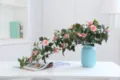 Artificial pink rose flower vine detail with blue ceramic vase for home decor and wedding setup. - Pink