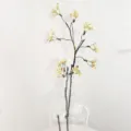 Close-up detail shot of artificial white berry floral branch in clear glass vase decor. - Yellow