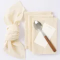 Close-up detail of cream wrinkled table napkins with wooden handle spoon and decor card for decor. - 42*42 / Khaki