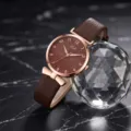 Elegante orologio da polso al quarzo da donna con cinturino in pelle marrone e dettagli a fiocco. - Caffè