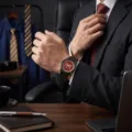 Detalle en la muñeca de un reloj de cuarzo para hombre con esfera roja y correa de metal negro. - Rojo