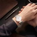 Detalle en primer plano de reloj de mujer con esfera blanca y correa de malla magnética. - Blanco