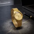 Primer plano de reloj de cuarzo dorado con esfera de pedrería y correa de acero inoxidable. - Caja Dorada Esfera Dorada