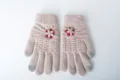 Close-up view of the knitted touchscreen winter gloves featuring delicate floral applique. - One Size / Off White