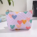 Close-up detail of the cute purple leather coin purse featuring colorful heart patterns and zipper. - Purple