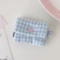 Vista dettagliata della custodia per cuffie a quadri blu e bianchi, grazioso bottone a cuore e anello. - Quadri blu