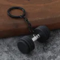 Close-up of a creative metal dumbbell keychain with black silicone weights and keyring. - Black