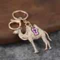 Detailed view of sparkly rhinestone camel keychain with pink saddle, gold tone metal keyring. - Camel 2 White Rhinestone Pink / Pink