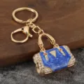 Close-up detail of luxury blue rhinestone handbag metal keychain pendant and keyring accessory. - KC Gold + Blue