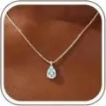 Close-up detail of a stunning pear-shaped light blue gemstone pendant on a gold box chain. - 14k / March - Gold