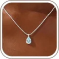 Close-up of a stunning pear-shaped light blue zircon pendant necklace on a delicate silver box chain. - 14k / March-Silver