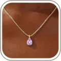 Close-up detail of a stunning gold-plated pear-cut purple cubic zirconia pendant necklace. - 14k / June - Gold