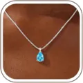 Close-up of pear-shaped blue zircon pendant necklace worn on neck, elegant detailed jewelry shot. - 14k / December-Silver