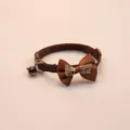 Close up of brown pet collar detail, featuring cute plaid bowknot and small bell accessory. - Brown
