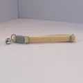 Close-up detail of the cute yellow checkered pet collar with cat face buckle and bell. - Beige