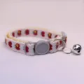 Close up of cute pet collar with apple print, lace trim, grey buckle and silver bell. - White and Red Apple