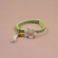 Close-up detail of green pet collar featuring white knitted flower, bell and tassel. - Green