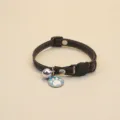 Close-up detail of the denim pet collar, featuring a cute blue paw pendant and silver bell. - Black