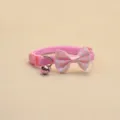 Gros plan détaillé du joli collier pour animal rose avec nœud rayé et cloche métallique. - Rose