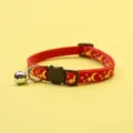 Red pet collar featuring gold moon and star print, black cat buckle, and cute bell detail. - Red