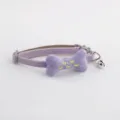 Purple pet collar detail featuring stuffed bone, yellow embroidered hearts, and metal bell. - Purple