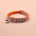 Close-up view of the orange floral cat collar featuring a safety buckle and silver bell. - Orange