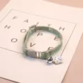 Detailed close-up view of a green fabric pet cat collar featuring a cute bell and pendant. - Green Stitching