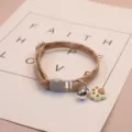 Brown pet cat collar detail view, cute paw charm and bell, adjustable design for small pets. - Light Khaki Stitching