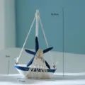 Vista dettagliata del modellino di barca a vela in legno con stella marina blu e rete in corda. - Stile Barca Stella Marina