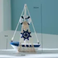 Vista dettagliata della barca a vela in legno in miniatura con rete e timone blu e bianco. - Stile Barca Salvagente