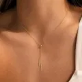 Primer plano detallado de un delicado collar Y dorado con cuenta deslizante y colgantes. - Estilo de Borla con Cuenta Ajustable (Estilo 2)