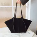 Λεπτομερής όψη της μαύρης σουέτ τσάντας tote με μοναδικό σχήμα φτερού και διπλούς ιμάντες. - Μαύρο