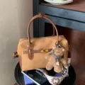 Braune Wildleder Boston Tasche mit Griffen, schickem Metallschloss und süßem Bärenanhänger. - Mit Anhänger / Braun