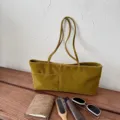 Detail view of the elegant velvet shoulder tote bag with front pocket and dual straps. - Mustard Yellow