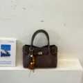 Donkerbruine suède emmertas met draaisluiting en kraalhangertje, stijlvolle schoudertas voor dames. - Met Hanger / Koffie