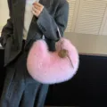 Vue détaillée du sac porté épaule croissant en peluche rose avec un joli charm cœur. - Style Avec Pendentif / Rose