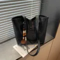 Vista detallada del bolso tote de cuero negro con dije de cuentas de madera para estilo diario. - Con Colgante / Negro